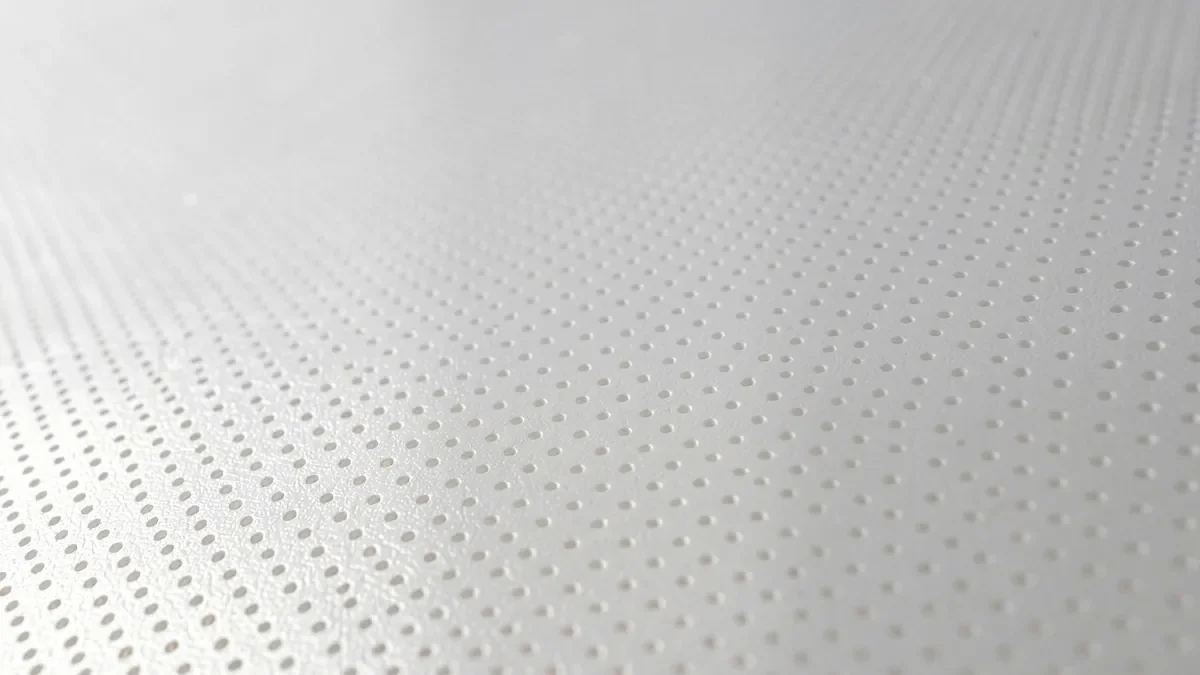 Zbliżenie makro na białą, matową membranę akustyczną sufitu napinanego z widoczną strukturą mikrootworów perforacyjnych redukujących pogłos.